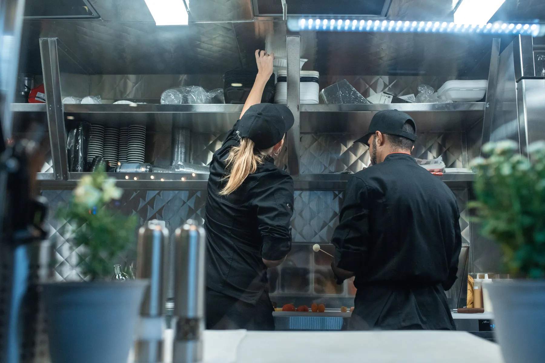 Cuisiniers au travail dans une cuisine professionnelle équipée d'une hotte d'extraction