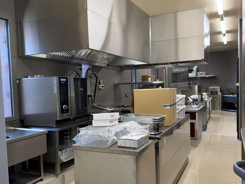 Hotte professionnelle inox sur mesure au-dessus de la ligne de cuisson d'une cuisine de restaurant