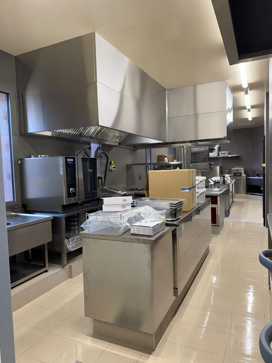 Hotte professionnelle inox sur mesure au-dessus de la ligne de cuisson d'une cuisine de restaurant