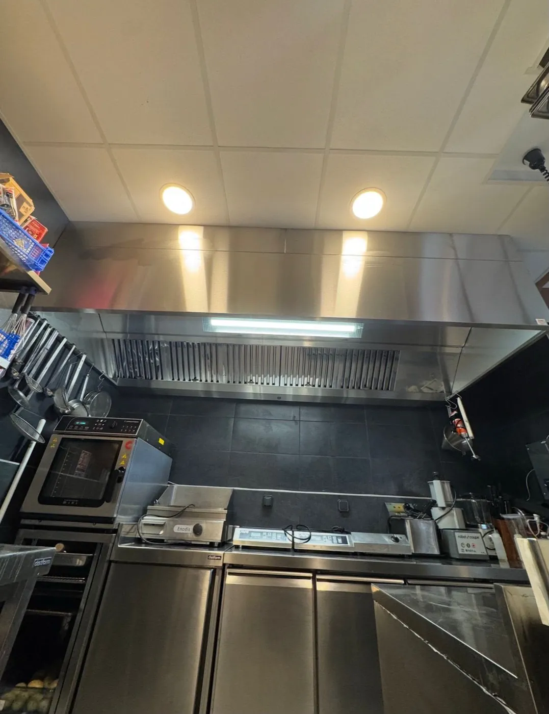 Hotte murale inox à filtres à chocs avec éclairage au-dessus d'un plan de cuisson
