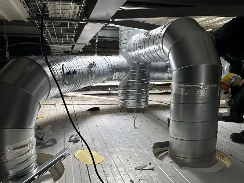Réseau de conduits d'extraction galvanisés en cours d'installation en faux plafond